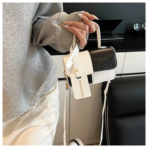Detail of a chic black and white leather mini crossbody bag with a fashion tag