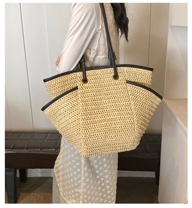 Detailed side view of a straw tote bag featuring leather trim and a spacious side pocket