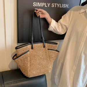 Detail of the woven tote bag showing black leather straps and side pocket functionality