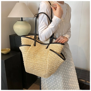 Detail of minimalist straw tote bag featuring contrast black PU leather trim and weaving texture