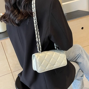 White quilted leather crossbody bag with silver chain strap worn over a black blazer