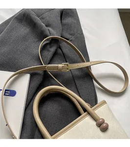 Vue détaillée du sac tressé crème avec pendentifs ronds et bandoulière réglable