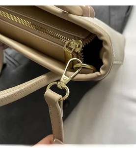 Gros plan détaillé sur les ferrures dorées et la fermeture éclair d'un sac à main beige