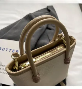 Vue détaillée d'un sac cabas beige avec poignées rondes, perles brunes et fermeture dorée