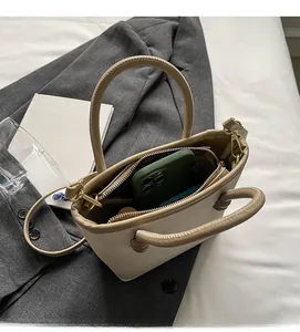 Détail d'un sac cabas beige texturé montrant un intérieur spacieux avec smartphone