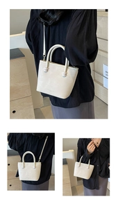 Détail d'un sac seau crème avec texture ondulée et bandoulière amovible réglable