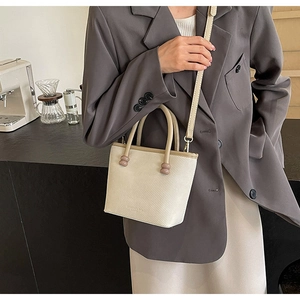 Détail du sac bandoulière crème avec tissu texturé et accents de sphères brunes uniques