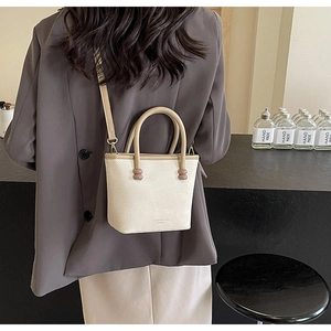 Détail du sac seau blanc cassé avec poignée marron et perles décoratives roses