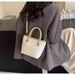 Détail du sac bandoulière en cuir blanc cassé avec perles roses sur la poignée de main
