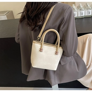 Détail du sac à bandoulière blanc cassé avec poignée kaki et accents décoratifs perlés