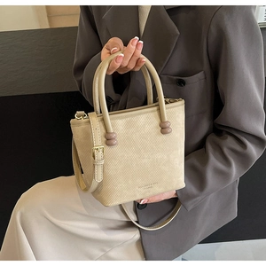 Détail du sac à main beige en cuir texturé avec poignée perlée et bandoulière réglable