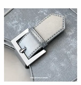 Detailansicht der silbergrauen Stofftasche mit polierter Metallschnalle und Lederriemen