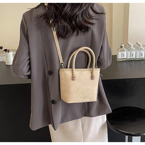 Détail du sac seau beige avec deux poignées et perles roses décoratives