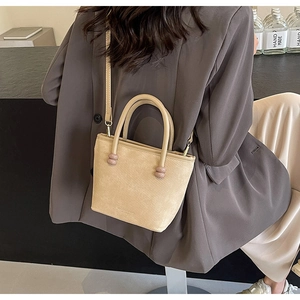 Détail du sac à main beige en cuir texturé avec perles mauves et marquage délicat