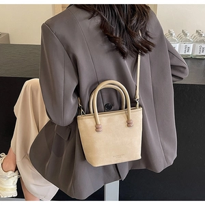 Sac seau beige chic avec texture sergée et détails sphériques porté avec une tenue élégante