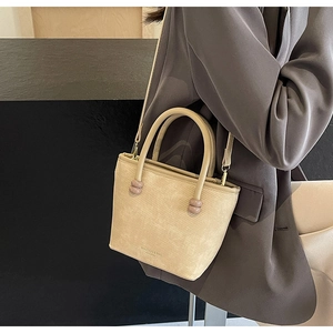 Détail du sac bandoulière crème avec ornements sphériques violets et logo de marque