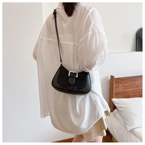 Detail of black crescent shoulder bag with leather splicing and silver buckle accent