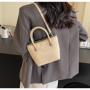 Détail du sac cabas crème avec texture diagonale fine et perles élégantes sur l'anse