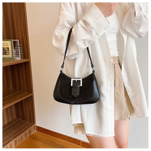 Close-up of black leather crescent underarm bag with silver buckle on a model