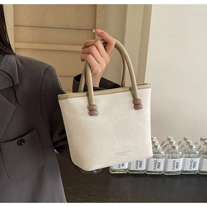 Détail d'un mini sac beige texturé avec poignées rondes et accents de perles rondes