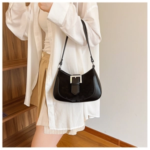 Detail of black crescent shoulder bag with silver buckle worn in a retro indoor setting