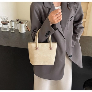 Détail du sac à main blanc crème avec texture ondulée et perles roses sur l'anse