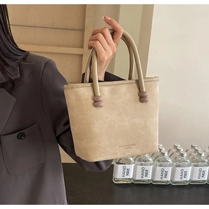 Détail du sac cabas beige avec rayures texturées et accents sphériques sur la poignée