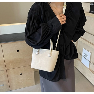 Détail du sac seau blanc crème avec texture en cuir et décoration de perles rondes
