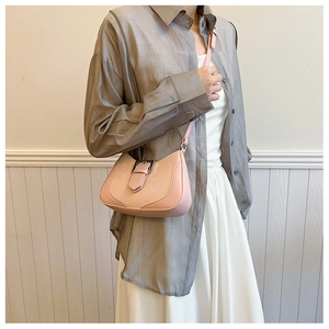 Pink crescent shoulder bag worn by model with gray shirt and white long skirt