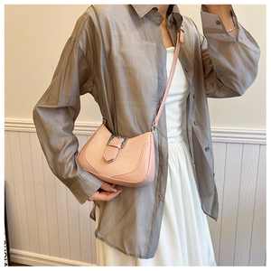 Detail shot of pale pink crescent bag with metallic buckle and slim shoulder strap