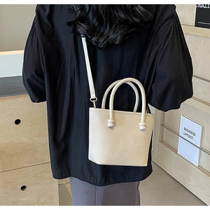 Détail d'un mini sac cabas crème texturé avec poignées rondes et fine bandoulière