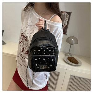Nahaufnahme eines schwarzen Mini-Rucksacks mit Steppmuster, Nieten und Kettenriemen