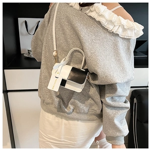 Close-up of a mini black and white patchwork crossbody bag with a fashion logo tag