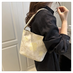 Close-up of floral embroidery texture on off-white canvas tote bag held by model