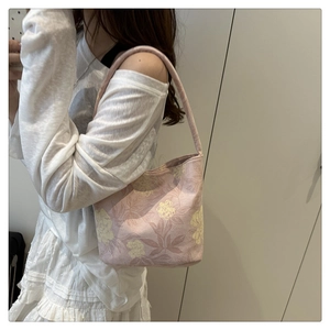 Détail de broderie florale rose sur un sac cabas vintage en toile porté par un mannequin