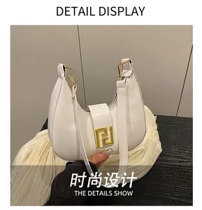Detail of white pebbled leather crescent bag with gold geometric metal lock and fine stitching