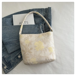 Detailansicht der bestickten Blumen-Bucket-Bag aus Leinen auf lässigem Stoffhintergrund