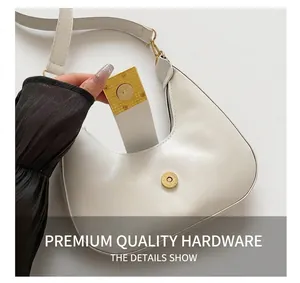 Close-up of golden magnetic buckle on white leather crescent bag showing high-end hardware