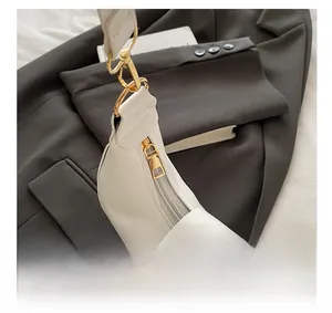 Close-up of smooth golden metal zipper and premium white leather on a crossbody bag