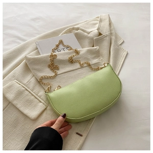 Detail view of light green crescent saddle bag featuring lychee grain faux leather texture