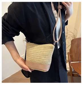 Detail shot of beige woven crossbody bag with leather base held by a model