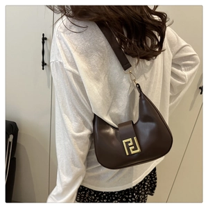 Detail view of a dark brown leather hobo bag featuring a gold buckle on the shoulder strap