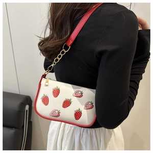 Detail of strawberry print shoulder bag with red piping and gold chain strap