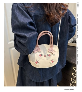 Detalle de bolso con forma de gato con lazo rosa y correa de cadena metálica dorada