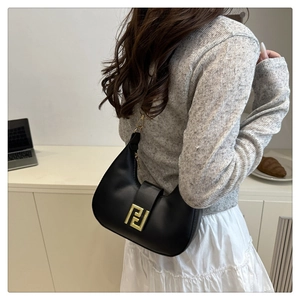 Detail of black semi-circle leather bag with golden buckle and detachable strap