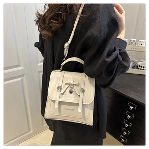 Detail of beige mini crossbody bag with leather bow and heart charm on flap