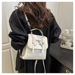 Detailed back view of model wearing the cream bow backpack with heart metal pendant