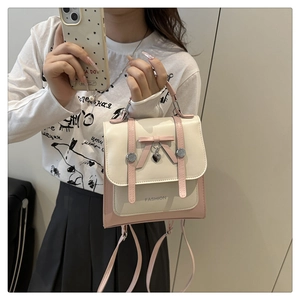 Detail of elegant cream and pink handbag featuring a decorative bow and heart pendant