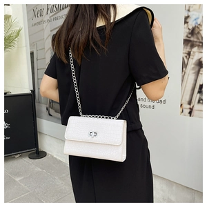 Detail showing white crocodile texture faux leather with silver metal twist lock and chain