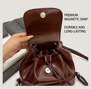 Detail of glossy brown PU leather backpack featuring drawstring and magnetic buckle closure